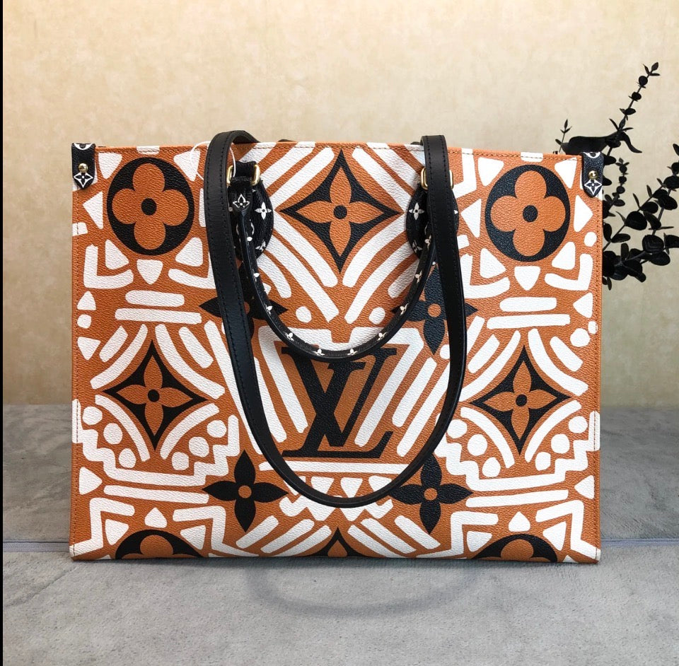 A Louis Vuitton tote bag featuring a bold orange, white, and black geometric monogram pattern, displayed on a gray surface against a beige background.