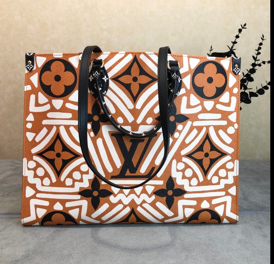 A Louis Vuitton tote bag featuring a bold orange, white, and black geometric monogram pattern, displayed on a gray surface against a beige background.