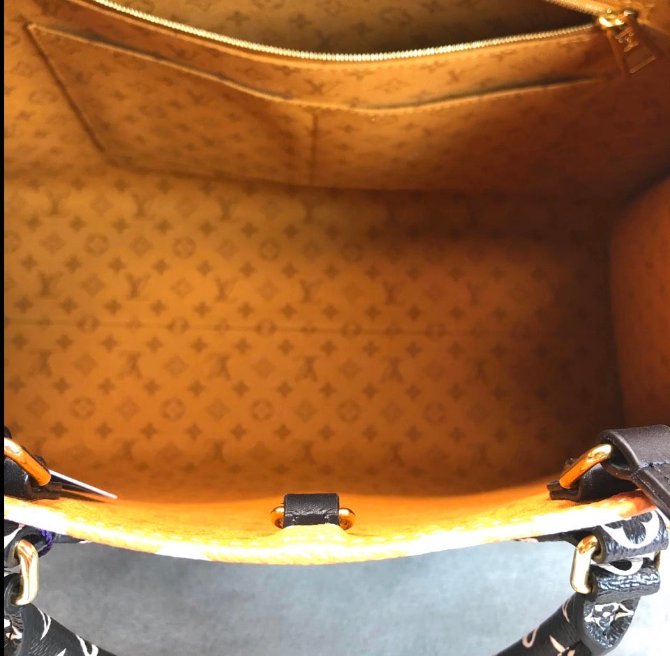 Close-up view of the interior of a Louis Vuitton handbag, showing the signature monogram canvas lining, a zippered top, and part of the black and white patterned shoulder strap.