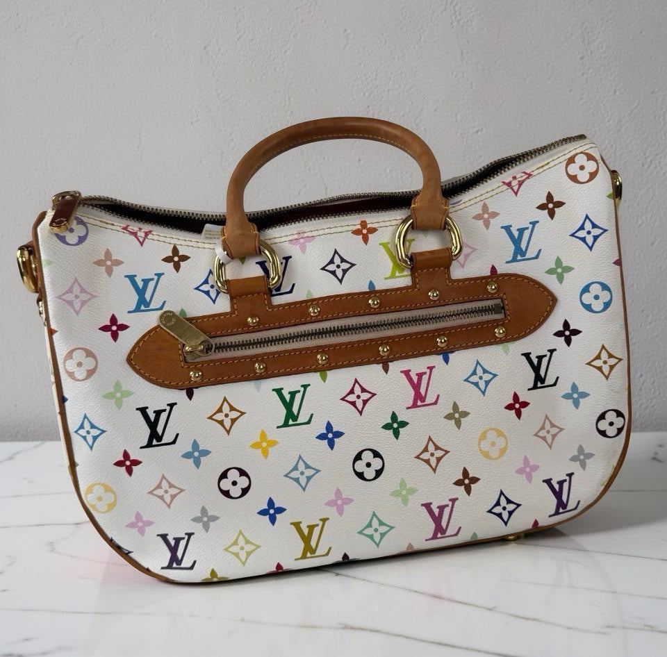 A Louis Vuitton monogram handbag in white coated canvas with multicolor printed motifs and tan leather trim, shown against a light gray wall and white marble surface.