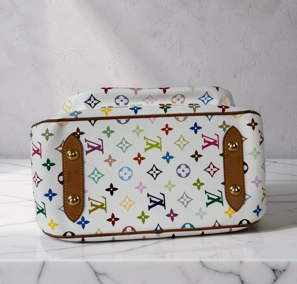 A Louis Vuitton monogram canvas box with a top handle, featuring brown leather trim and gold-tone hardware, displayed on a white marble surface against a textured gray wall.